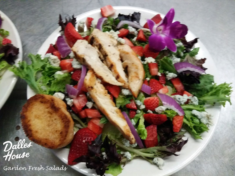 A large mixed green salad with local-fresh strawberries, crumbled blue cheese, chopped red onions,
			a grilled chicken breast sliced in strips, and a side of garlic toast